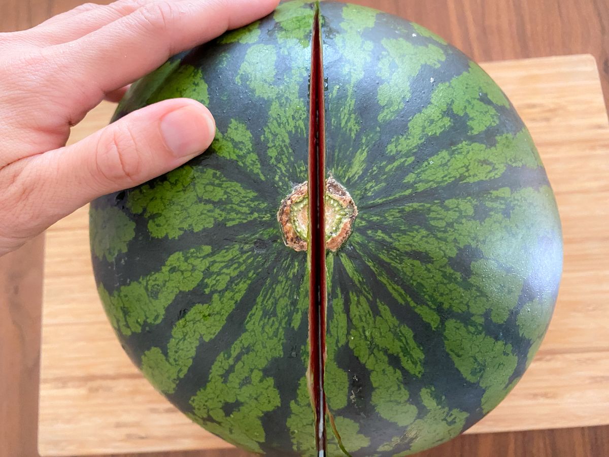 まな板の上でスイカを半分に切る真上からの写真