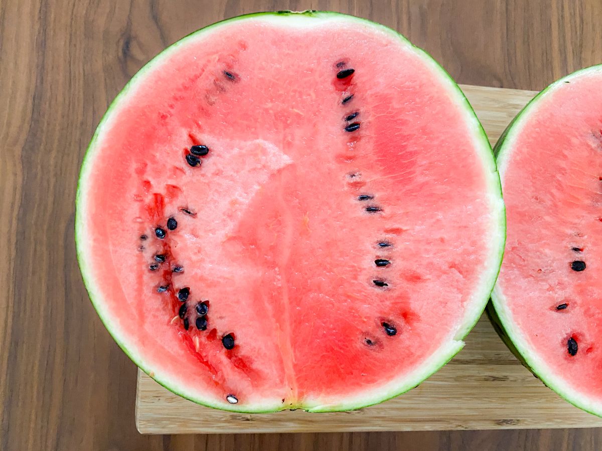 まな板にのせた半分スイカの断面と種の写真