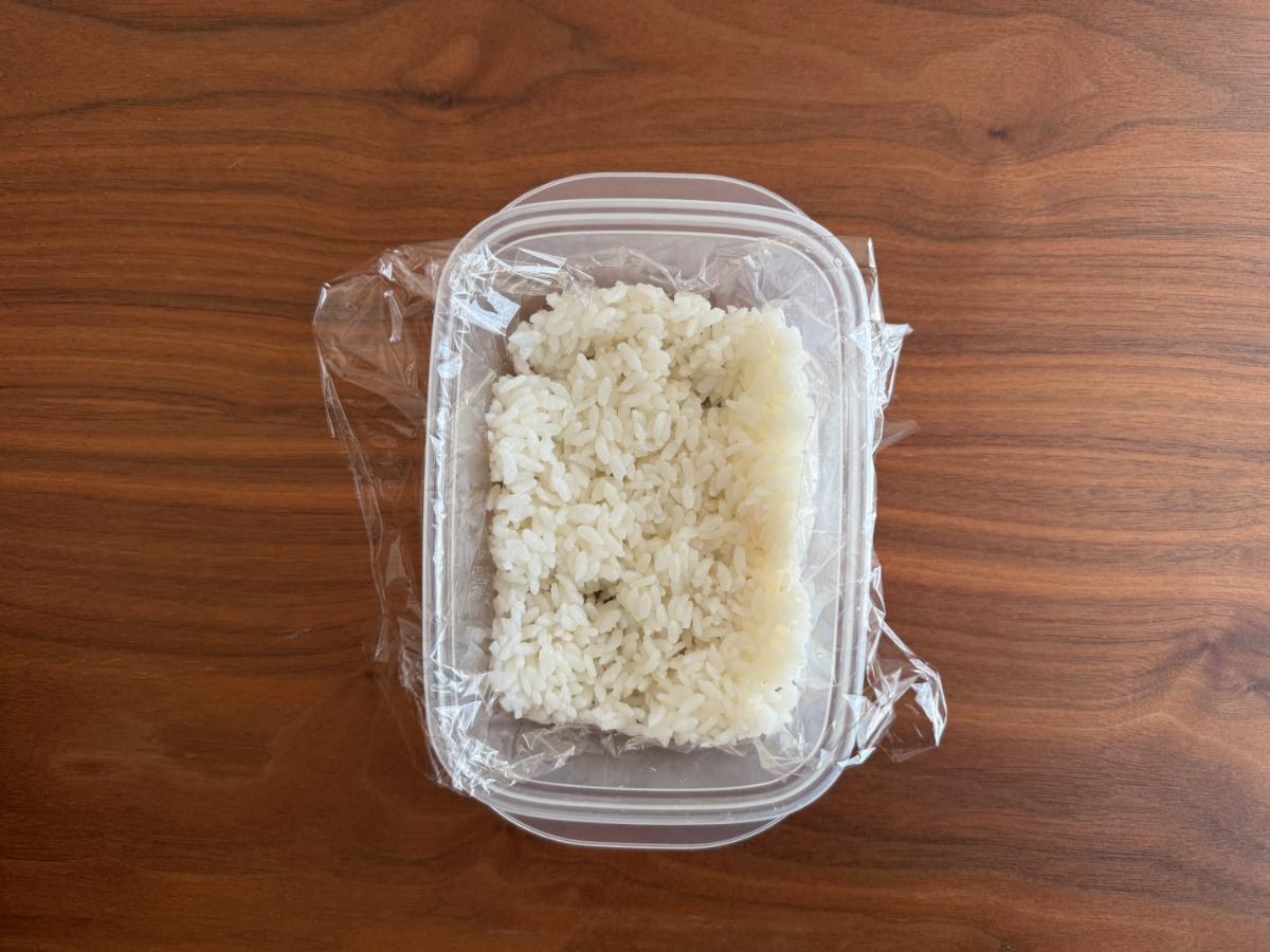 タッパーの底にご飯を半分広げたところ