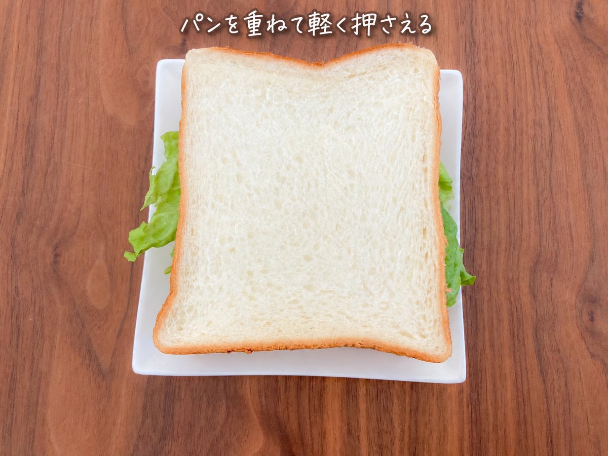 6)残りの食パンをかぶせて軽く押さえ、半分に切ります。